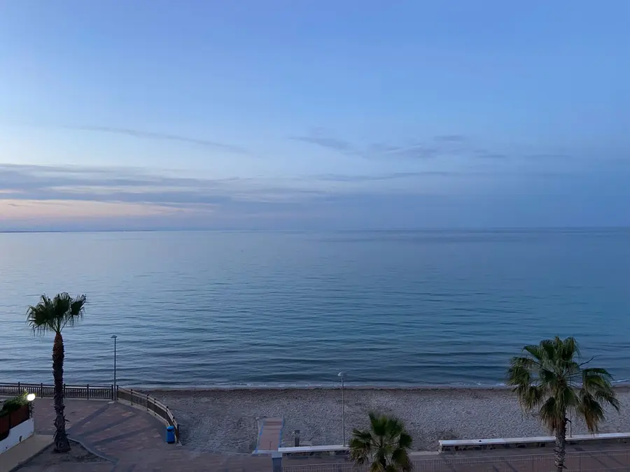 Café en la terraza con el mar todavía quieto.